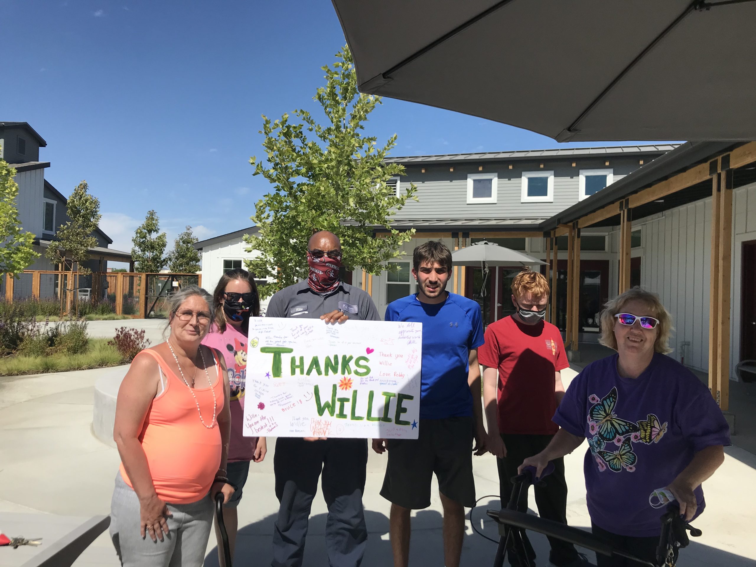 Della with other residents and Willie the SAHA Maintenance Tech. Sign that says "Thanks Willie"