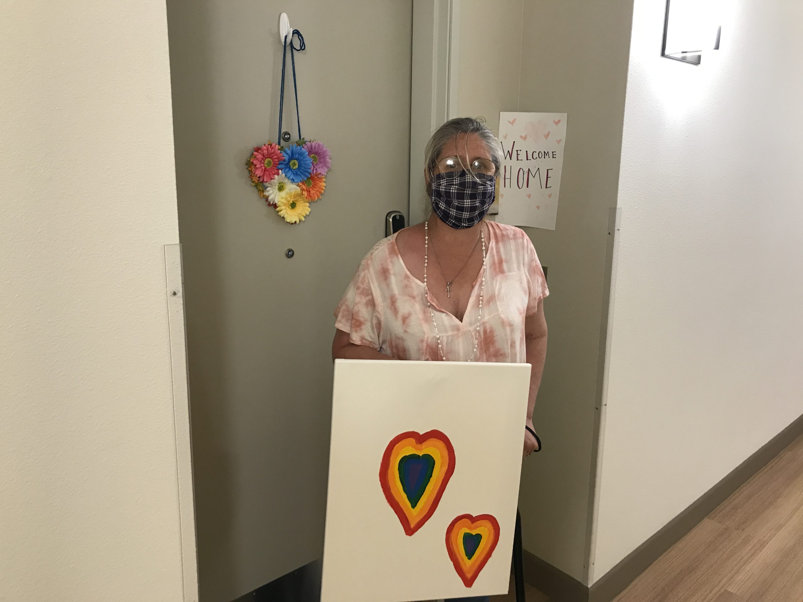 Della holding her painting of two hearts.