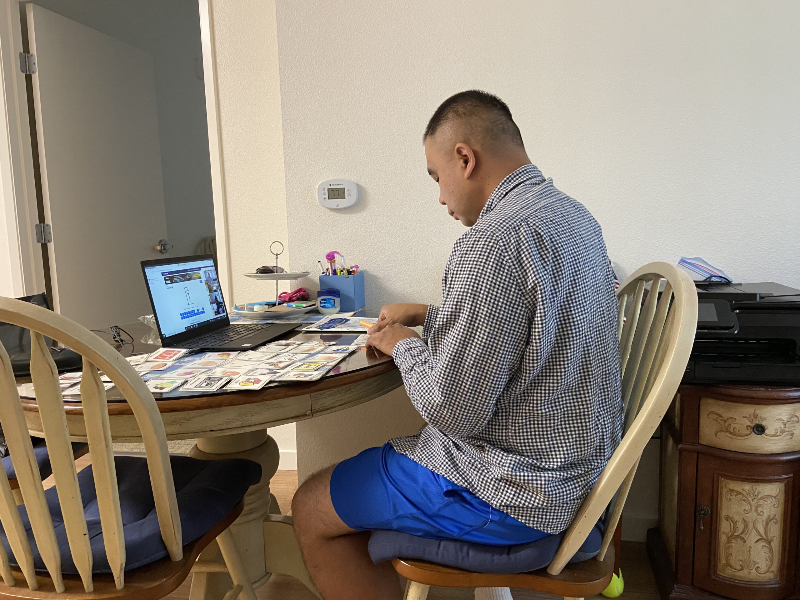 David sitting at his kitchen table with laptop, participating in his virtual day program.
