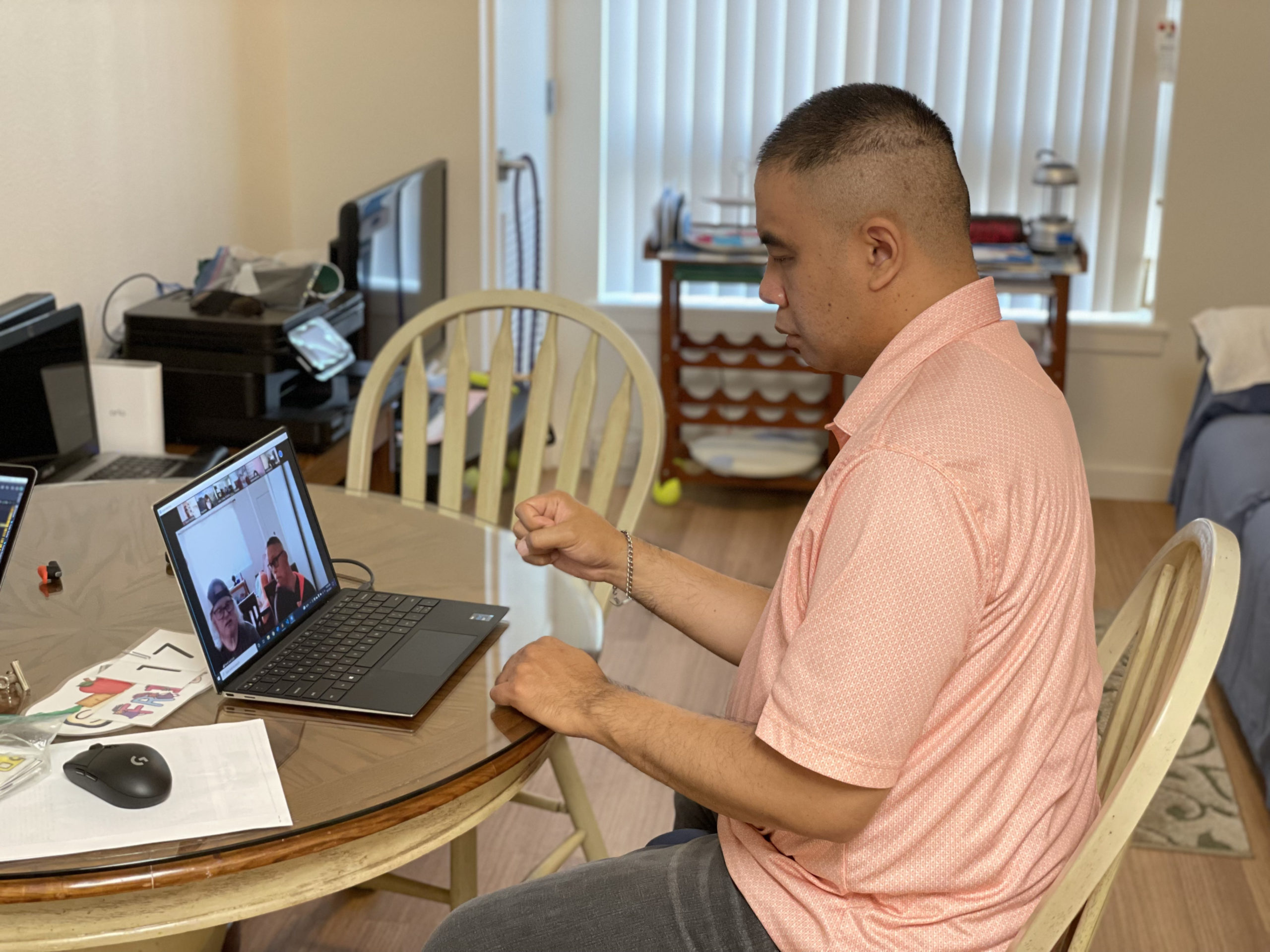 David sitting at his kitchen table with laptop, participating in his virtual day program.