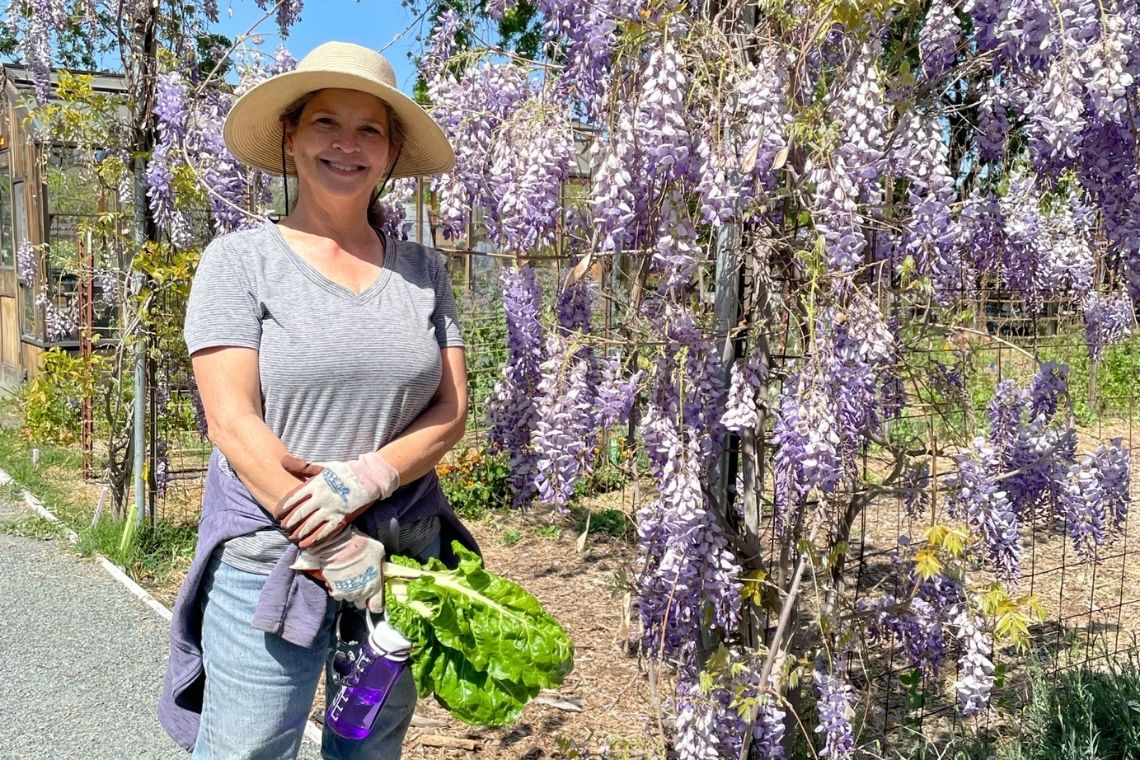 Louise standing next to wisteria vine in bloom