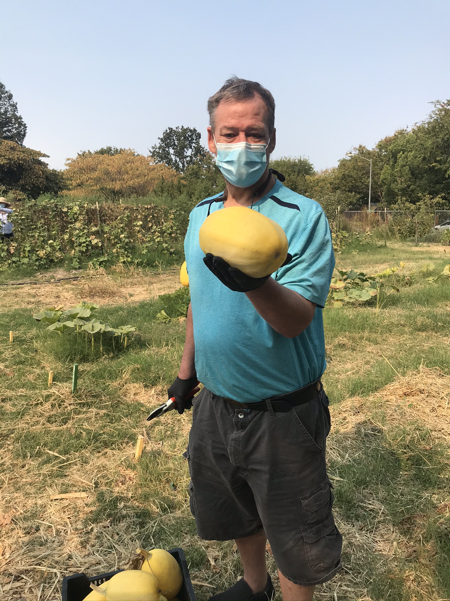 Bruce holding a winter squash at the Sunflower Hill Garden