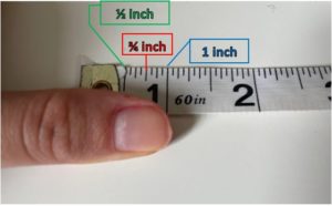Tape measure showing that from the tip of the thumb to the first knuckle is about one inch