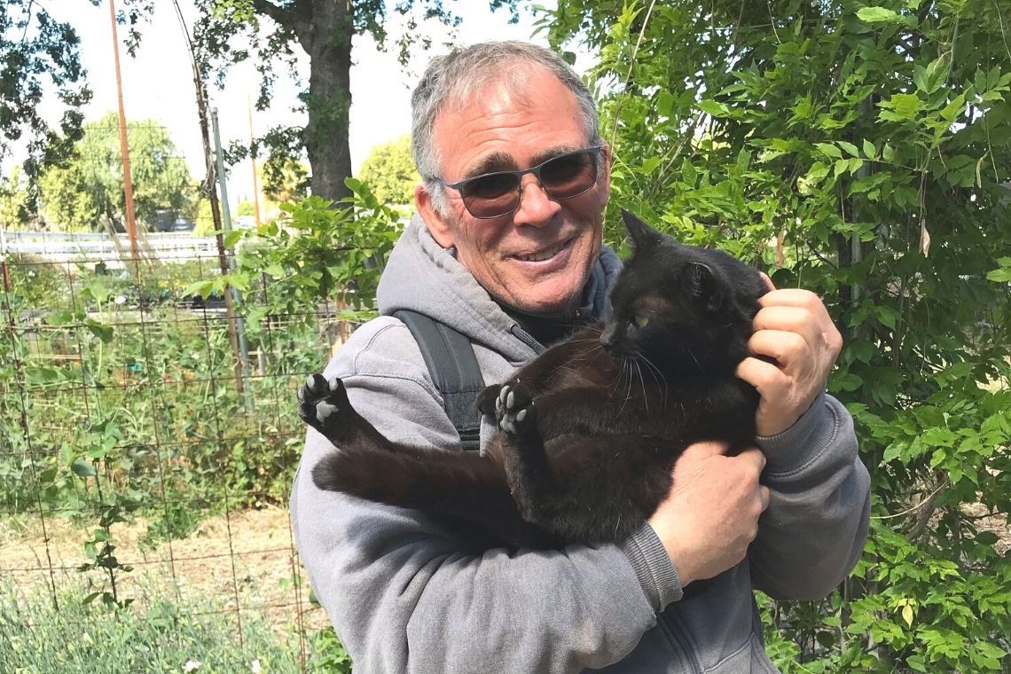 Tim holding Shadow the cat in the Sunflower Hill Garden.
