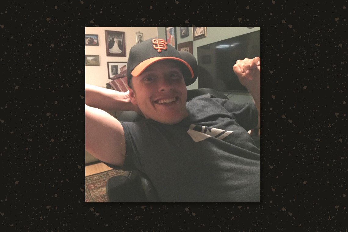 Picture of Kyle smiling with San Francisco Giants baseball hat.