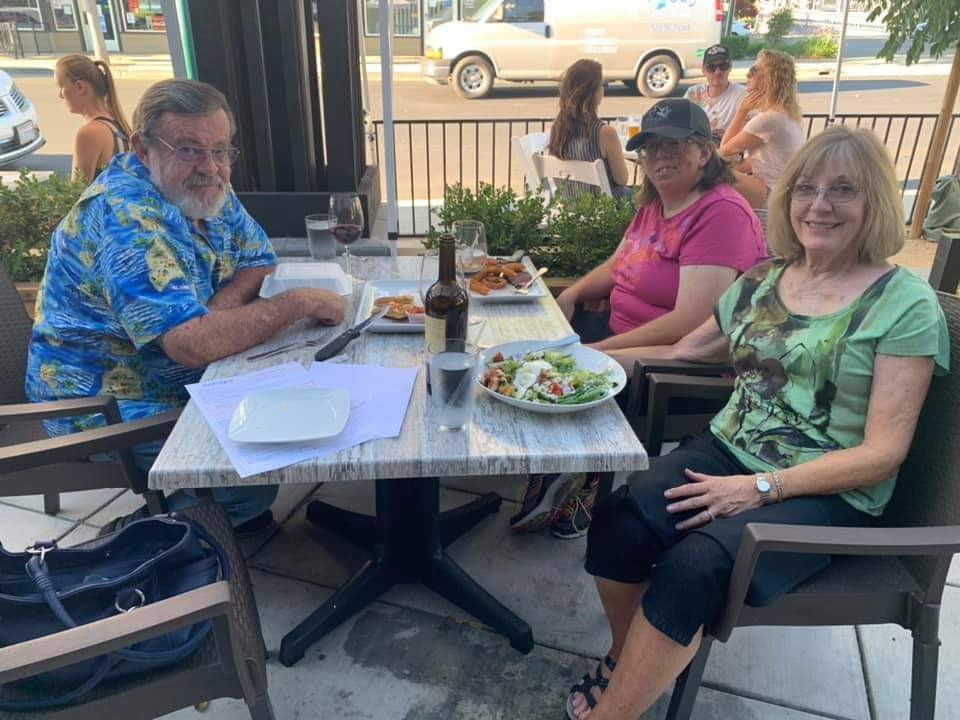 Shannon and her family sitting at a table outside, eating at a restaurant.
