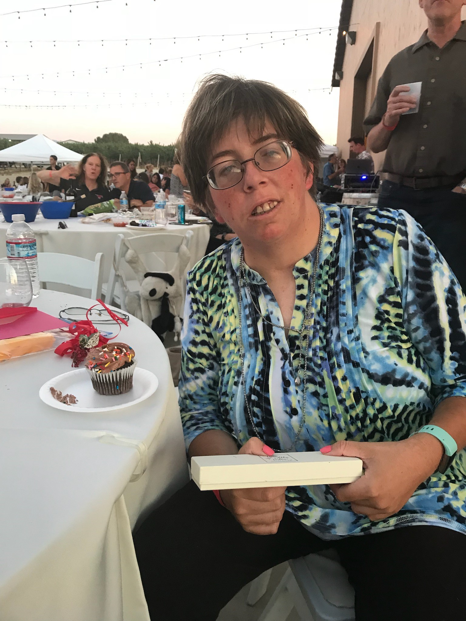 Shannon celebrating with a cupcake and a gift in her hand