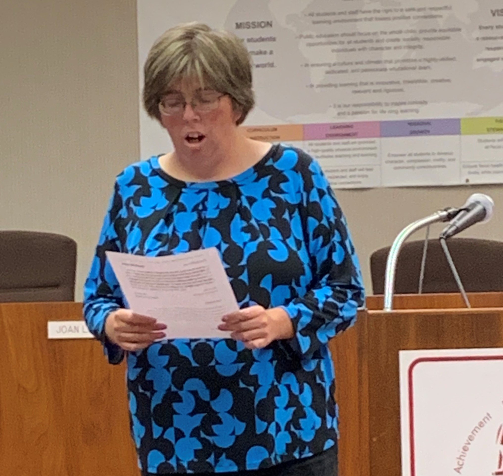 Shannon holding a paper and giving a thank you speech upon graduating from her internship program.